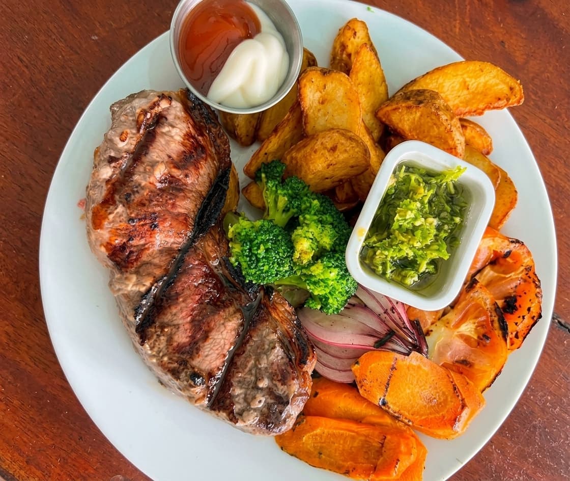 Churrasco a la parrilla con papas en gajo y verduras asadas